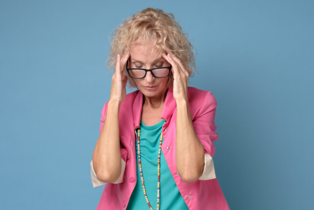 Mature caucasian woman in colored clothes touching her thead feeling stress
